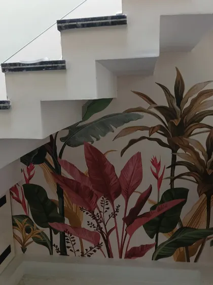 The space under a staircase is transformed with a colorful tropical plant mural. This is a creative way to add a pop of color and design to an often-neglected area.