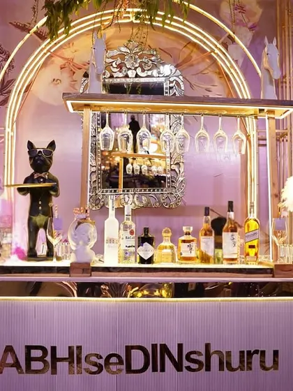 A close-up of the whimsical bar, showing the quirky bulldog statue holding a tray, set against the beautiful hand-painted floral backdrop.