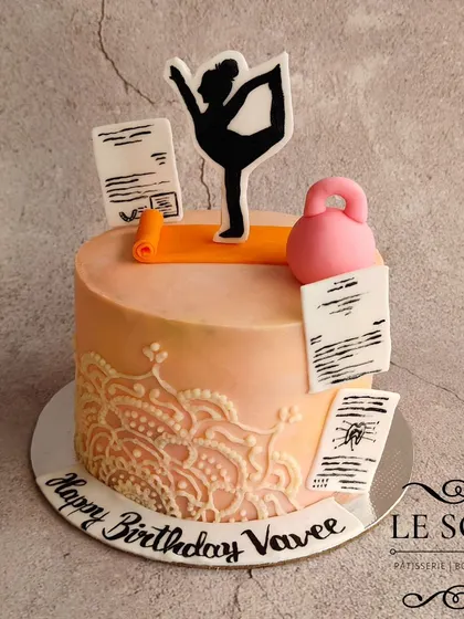 A fitness-themed cake designed as the perfect cheat meal. This half-kg Chunky Monkey cake (banana cake with walnuts and fudge) features a yoga theme with a kettlebell and intricate mandala stencil work.