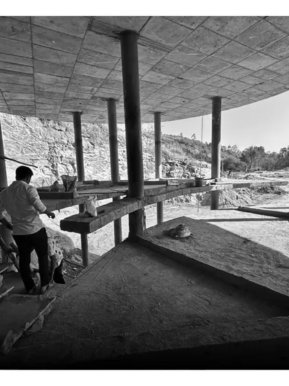 Workers on site, building the multi-level structure that seems to grow out of the rocky cliffside.