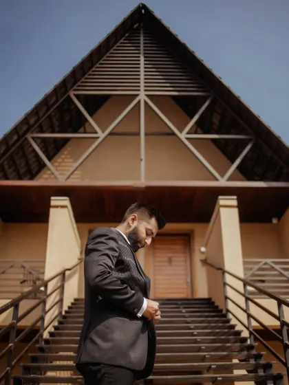 The groom, looking sharp in his suit, captured from a low angle against the modern architecture of the venue, creating a powerful and stylish portrait.