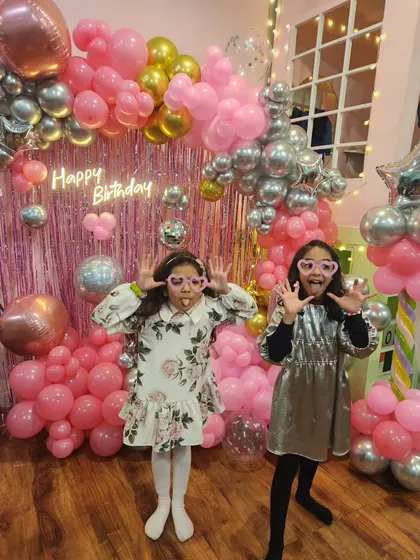 Getting ready to rock with a popstar-themed party. The backdrop is all about pink and silver, with shiny disco balls and a neon "Happy Birthday" sign.
