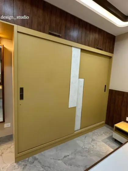 This bedroom makes a bold statement with a custom mustard-yellow sliding wardrobe. The design incorporates a unique white textured accent and is set against a backdrop of dark, fluted wood paneling for a dramatic and warm effect.