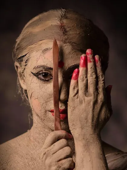 Holding a sculpting tool, this image symbolizes the act of shaping and being shaped. It reflects on how a woman's virtues and her 'cracks' are both part of her identity.