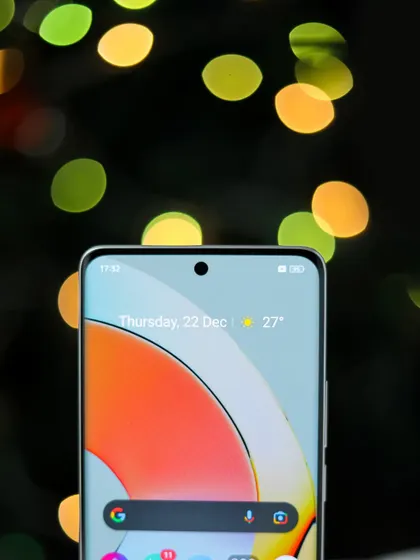 A close up of the realme 10 Pro+ 5G screen, with festive bokeh lights in the background for a Christmas theme.
