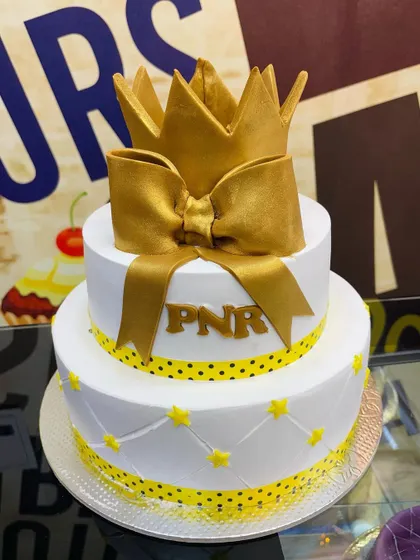 A royal 2.5kg two-tiered cake topped with a large golden crown and bow.