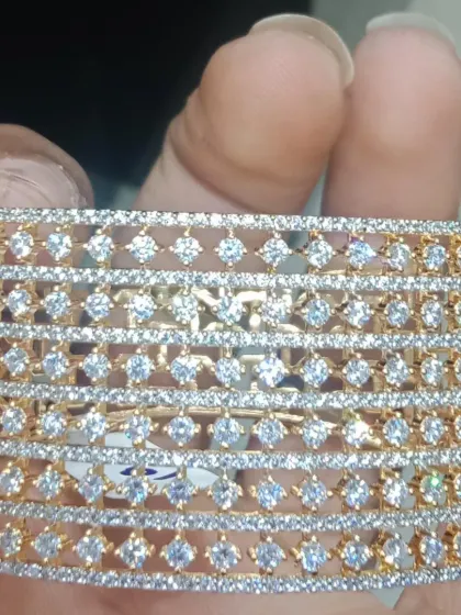 A wide, cuff-style bracelet with a beautiful jaali (net) pattern, studded with American diamonds. This is a bold and modern piece that makes a statement.