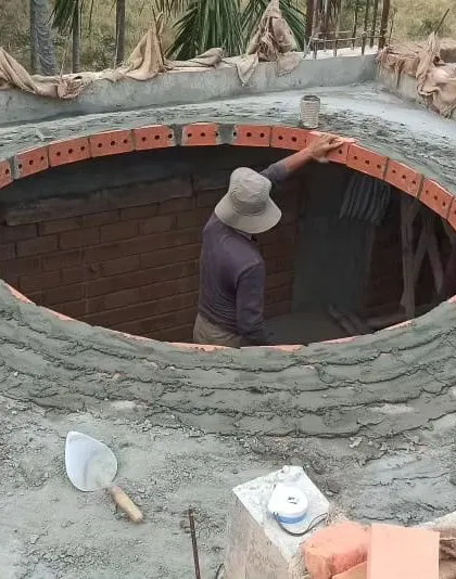 A mason carefully lays the first course of bricks for a circular dome, a process that requires immense precision and expertise.