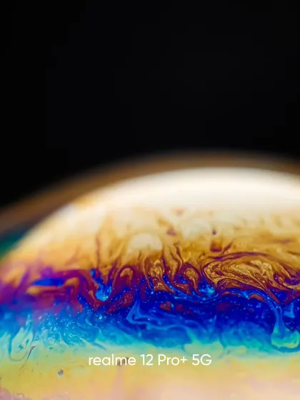 This macro shot captures the fiery swirls of yellow, orange, and blue on a soap bubble's surface, looking like a solar flare.
