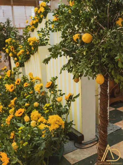 A detail shot showing a lemon tree and cascading sunflowers against a striped backdrop, highlighting the fresh and natural elements of the decor.