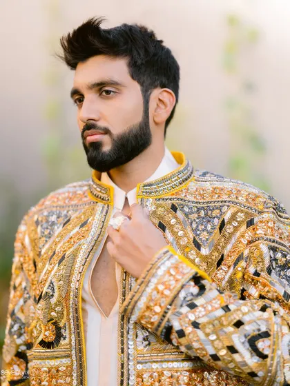 A handsome portrait of the groom in his intricately embroidered golden and black jacket, looking sharp and stylish.