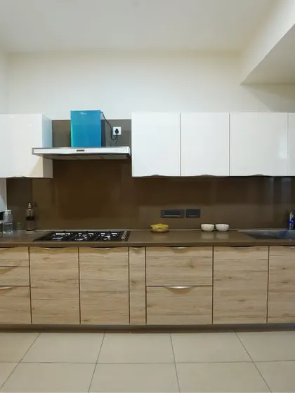 A spacious parallel kitchen with wood-laminate lower cabinets and glossy white upper cabinets. The design is clean, modern, and highly functional.