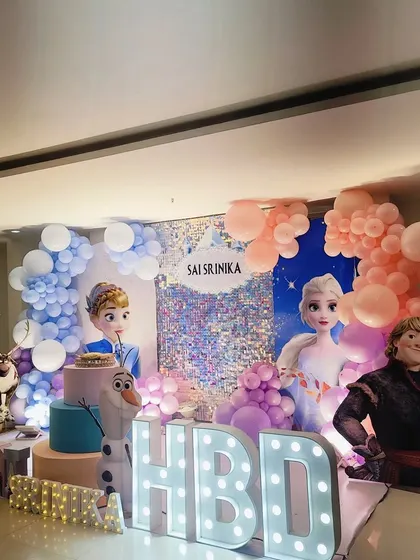 A full stage setup for a Frozen-themed 6th birthday, with all the main characters and "HBD" marquee letters.
