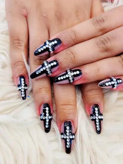 A bold and edgy design featuring black stiletto nails with a large cross made of sparkling rhinestones on each nail.