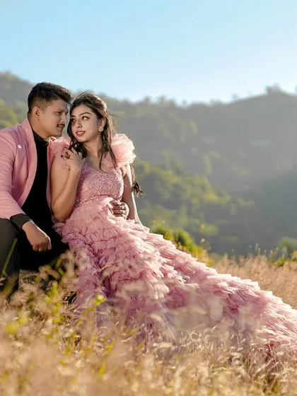 A romantic portrait of a couple on a sunlit hill, with the bride in a flowing pink gown. This highlights our work with destination shoots in beautiful natural landscapes.