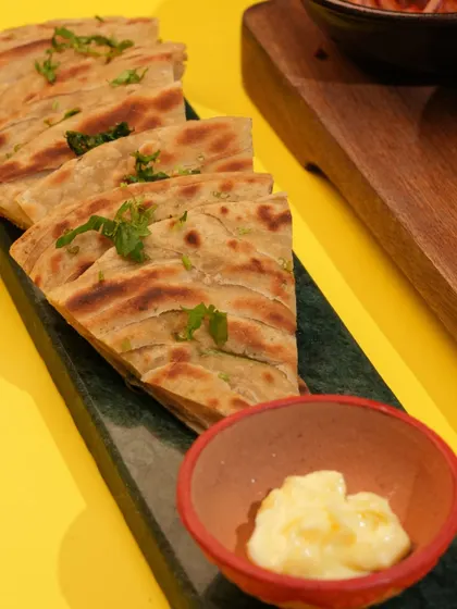 The perfect companion to any curry, my Lachha Parathas are flaky, layered, and brushed with ghee. Here they are served with a side of white butter.