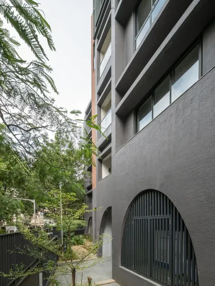 Close-up details of the ARCUS facade, highlighting the texture of the brickwork, the depth of the balconies, and how the structure was designed to accommodate existing trees.