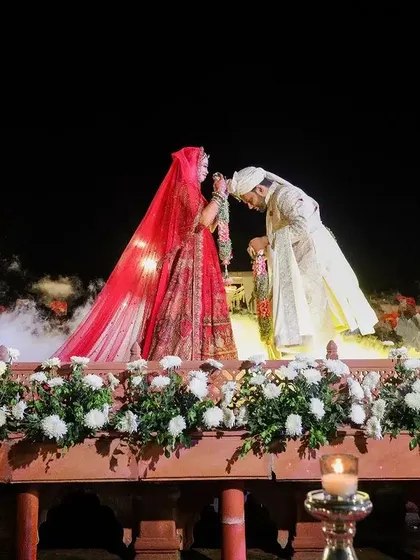 A romantic moment during the varmala ceremony, with the groom bowing his head.