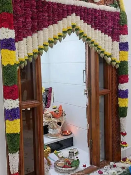 A colorful floral frame for a pooja room door. The design uses a variety of fresh flowers to create a vibrant and auspicious entrance for your home prayers.