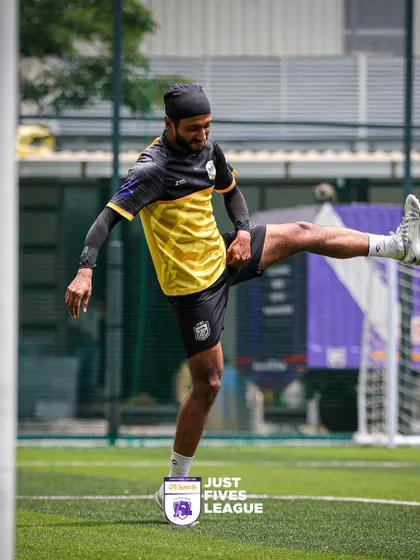 A player demonstrates impressive ball control and flexibility while warming up. We see a wide range of skill levels, but the passion for football is universal among all participants.