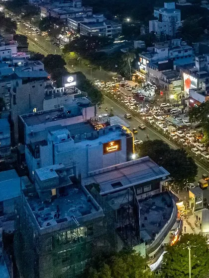 An aerial view of the Nalli store's urban context in Anna Nagar, Chennai, showing the heavy traffic and dense surroundings.