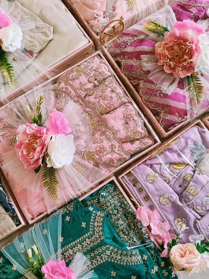 A colorful assortment of packed outfits for a wedding trousseau. The variety of prints and embroideries is beautifully complemented by our floral packing.