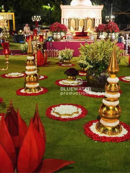 The lawn is decorated with large, illuminated red lotus installations and floral mandalas, creating a spectacular landscape for a night wedding.