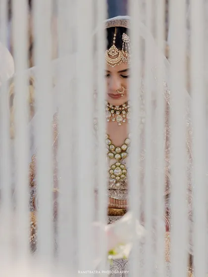 An artistic shot of the bride, seen through the floral strings of the mandap, during her Nikah ceremony.