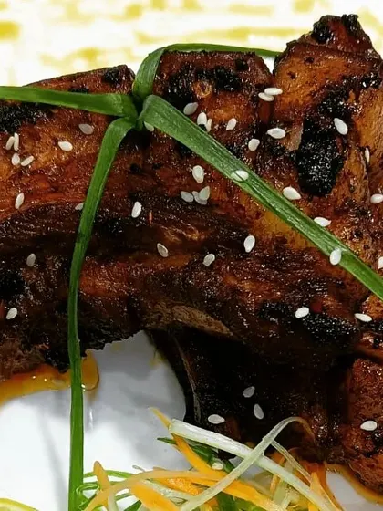 A close look at my smoked and glazed pork ribs. Each piece is cooked to be tender with a charred, flavorful exterior, then garnished with sesame.
