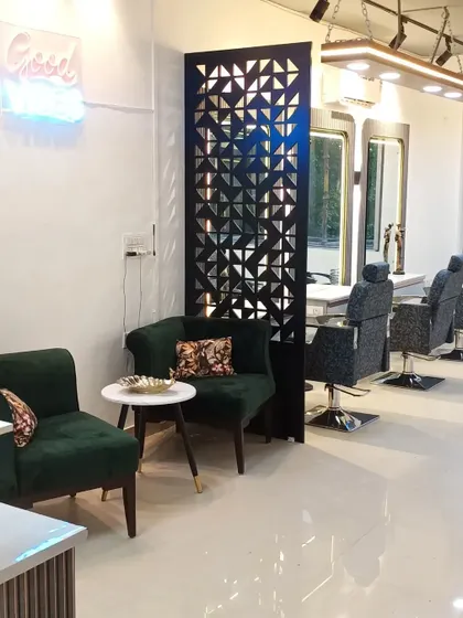 The waiting area at the Faridabad salon, featuring plush green velvet chairs and a stylish side table. We believe the client's experience begins the moment they step inside.