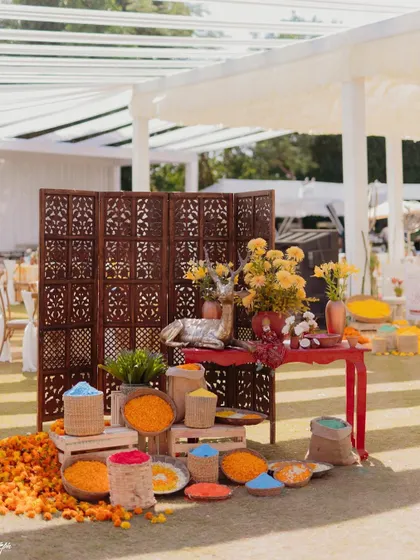 A station piled high with organic colors and marigold petals for the 'Haldi Holi' party. We love creating interactive elements that get guests involved in the fun.