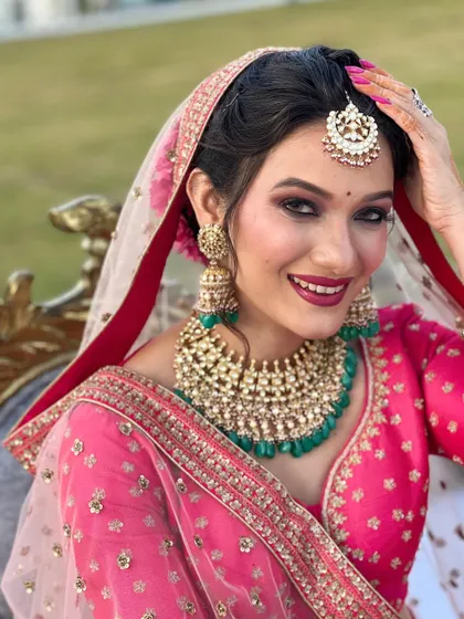 A radiant bride ready for her photoshoot. I created this look with a focus on bold, defined eyes and a vibrant magenta lip that perfectly matches her stunning pink lehenga. Her joyful smile says it all.