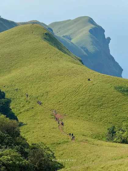 The iconic trail leading towards Bandaje Falls on a clear day, showing the scale of the Western Ghats.