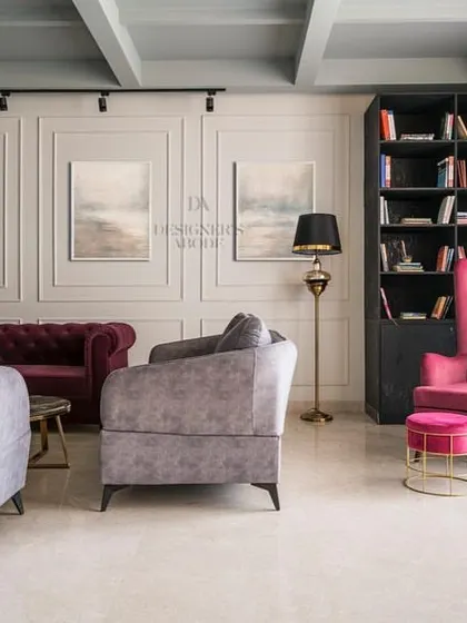 A full view of the living room from a featured project, showcasing the blend of grey, burgundy, and pink furniture. The design is a perfect example of our distinct, personality-driven approach.
