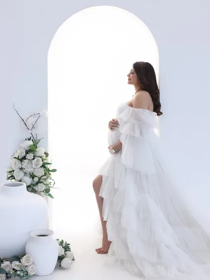 A profile of pure grace. The silhouette of the mom-to-be in this ethereal white gown against the bright archway creates a breathtaking and artistic portrait.