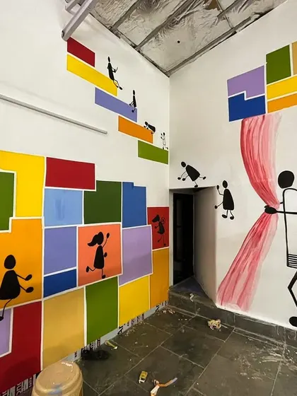 Another section of the Dharavi mural, where stick figures are seen pulling back a curtain, revealing more color and wonder.