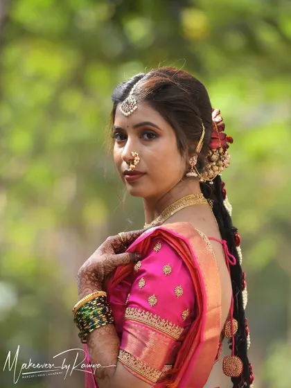 A beautiful profile shot of Santhoshi, showcasing her intricate bridal braid adorned with flowers. Traditional hairstyles are a key part of the complete bridal look.