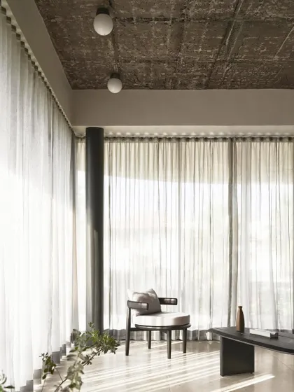 The living room of Pavilion House, where sheer curtains diffuse the bright sunlight, creating a soft and ethereal atmosphere.