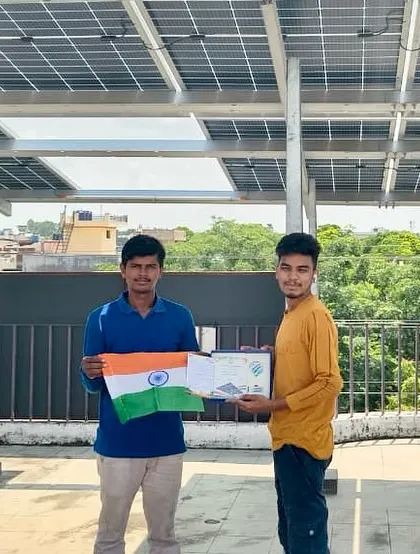 Two members of our community celebrating energy independence with the Indian flag under their new solar panels.