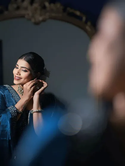 A candid moment of the model getting ready. The soft lighting highlights her glowing skin and the subtle details of her makeup.