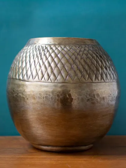 The Vihaan Metal Vase Planter features a unique combination of hammered and etched diamond patterns. This texture adds a contemporary yet traditional touch to your decor.