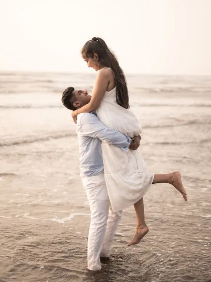 A joyful pre-wedding moment as the groom-to-be lifts his partner in the shallow waves of the sea. This photo is full of energy and happiness.