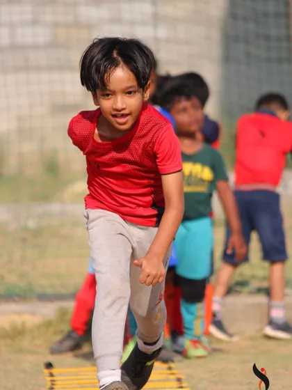 A young champion in action, running through a drill with intensity and focus during our football summer camp.