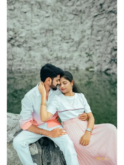 A couple sits on a rock by the quarry, sharing an intimate and tender moment. The soft colors of their outfits complement the natural scenery.