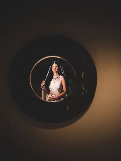 A unique, artistic portrait of the bride, Manu, seen through a circular opening, creating a sense of focus and intrigue.