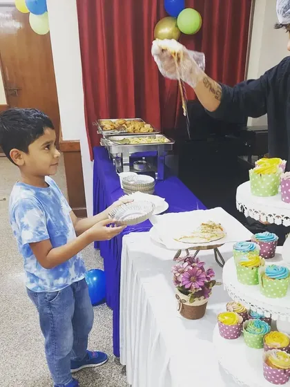 A young guest is delighted to receive a freshly made pizza slice at Ishaan's birthday party. Our live food stations are always a highlight, bringing an element of fun and freshness to the dining experience.