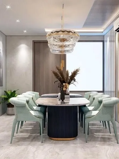 A sophisticated dining area with soft mint green chairs and a fluted table base. A layered glass chandelier adds a touch of glamour, creating an elegant space for meals.