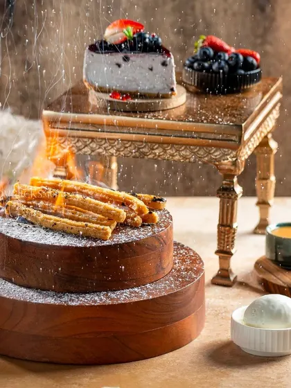 A moment of magic as powdered sugar is dusted over flaming churros, creating a dynamic and exciting dessert shot.