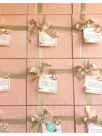 A large batch of New Year hampers, all elegantly wrapped in pink and gold. Each gift is adorned with a personalized note, ready to be delivered to clients or employees to kick off the new year on a high note.