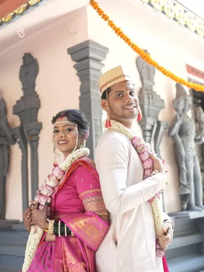A playful back-to-back pose. The bride's complete look, from makeup to saree draping, is captured beautifully.
